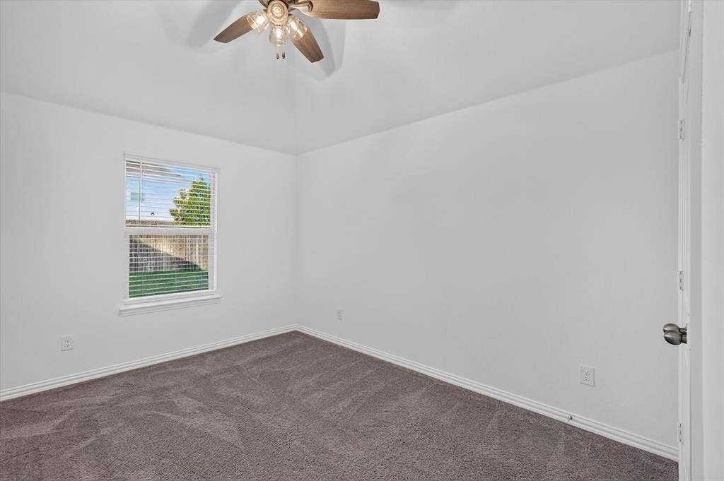 Room featuring vaulted ceilings, neutral carpeting, a dual-pane window, and a ceiling fan with integrated lighting