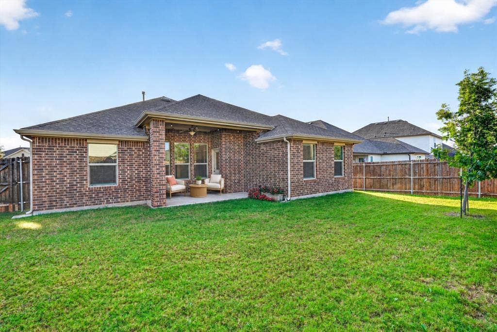 Brick exterior, covered rear patio, multi-pane windows, and wood-style privacy fencing