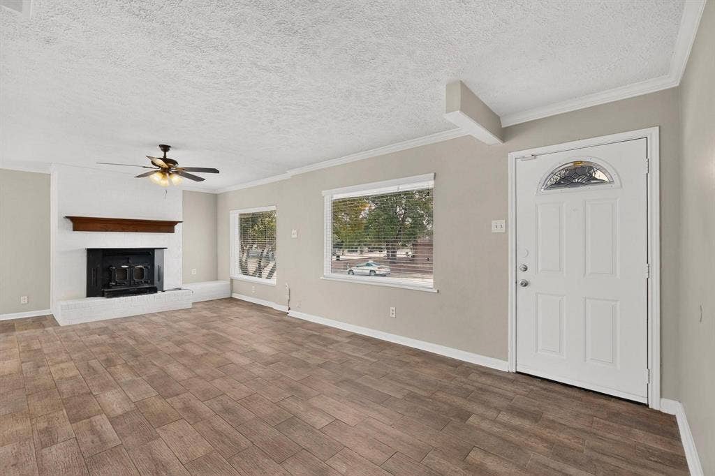 501 Starling Drive, Mesquite, TX 75149 A spacious living room featuring hardwood floors, a fireplace, a ceiling fan and wide windows, perfect for relaxation and gatherings.