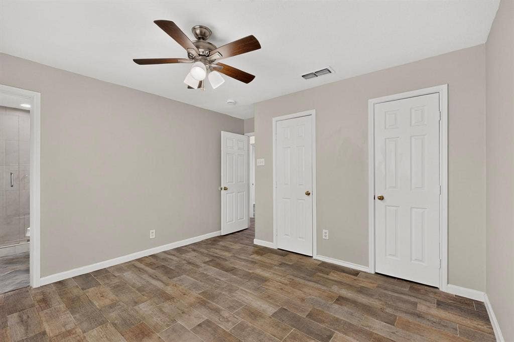 501 Starling Drive, Mesquite, TX 75149 Bright primary bedroom with a ceiling fan, hardwood floors, two separate closets and an en suite bath, perfect for relaxation.
