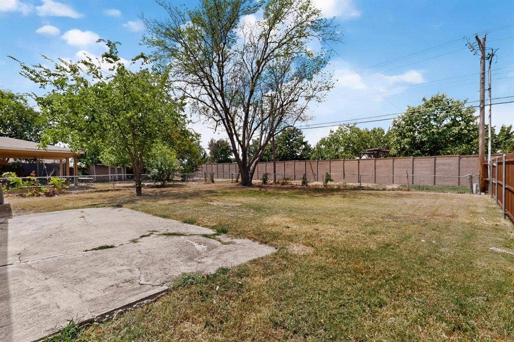 501 Starling Drive, Mesquite, TX 75149 A peaceful backyard scene with a patio featuring a chain link fence and vibrant trees, creating a cozy outdoor space.