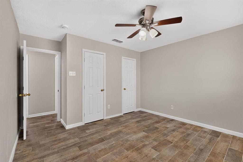 501 Starling Drive, Mesquite, TX 75149 Bright primary bedroom with a ceiling fan, hardwood floors and two separate closets, perfect for relaxation.