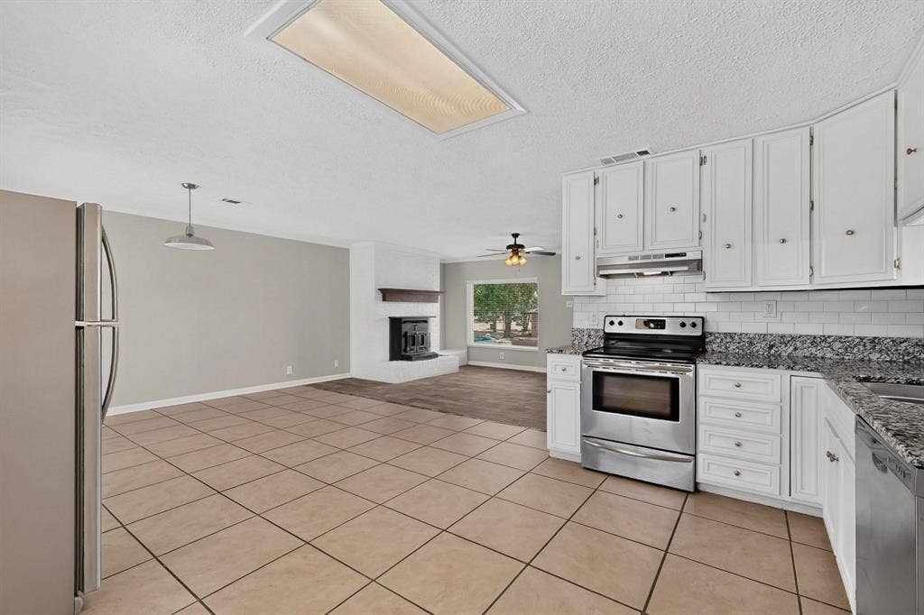 501 Starling Drive, Mesquite, TX 75149 Bright kitchen with sleek white cabinets, stainless steel appliances and tile flooring, creating a clean and modern atmosphere.