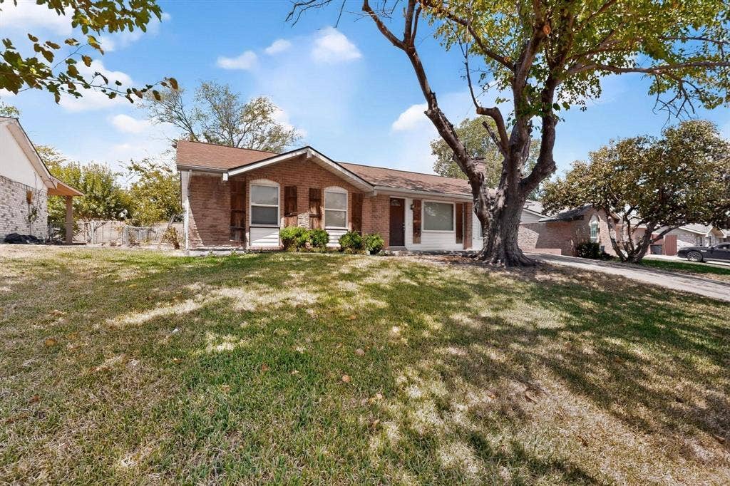 501 Starling Drive, Mesquite, TX 75149 A lovely brick residence with a wide yard and a mature tree, offering a peaceful and inviting outdoor space.