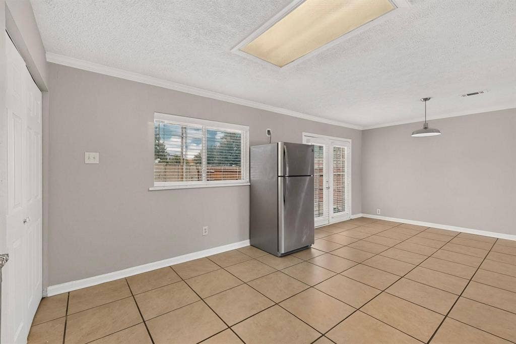 501 Starling Drive, Mesquite, TX 75149 Bright kitchen with a wide window, tile flooring and a stainless steel refrigerator, offering a fresh and inviting space.