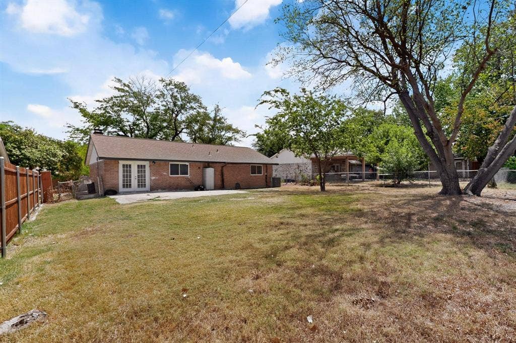 501 Starling Drive, Mesquite, TX 75149 A serene backyard with a patio featuring a wooden fence and lush green trees, creating a cozy outdoor space.