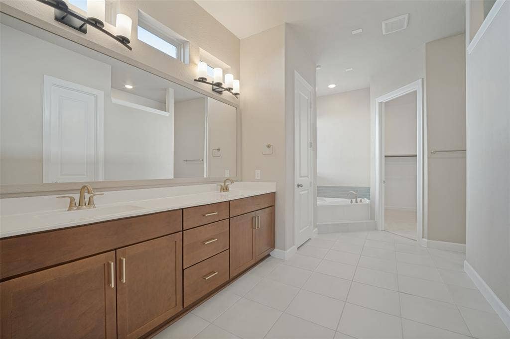 En suite primary bathroom with dual sinks, a separate soaker tub and walk in shower