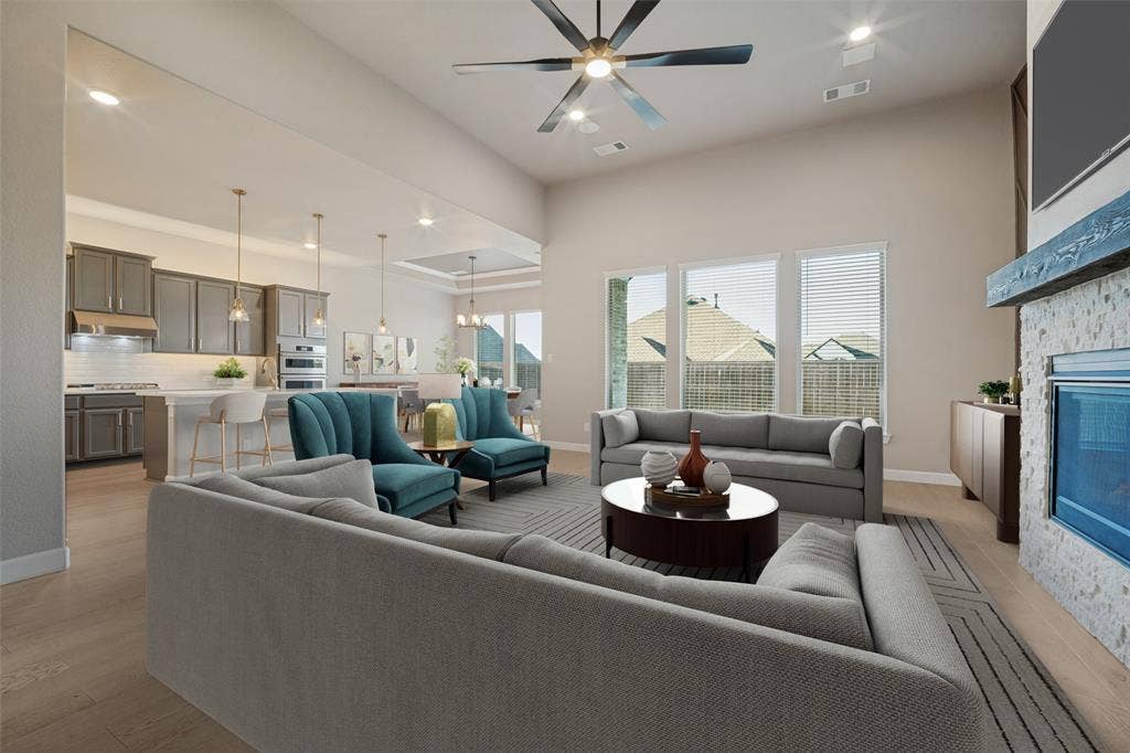 The living room features the same beautiful wood-look flooring, accent walls bookending a cozy fireplace, and flooded in natural light; Virtually staged
