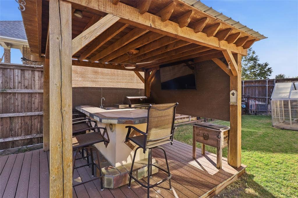 1614 Jeffrey Drive, Wylie, TX 75098 Outdoor Kitchen features custom cedar arbor, gas grill, sink, TV, bar seating, and refrigerator.