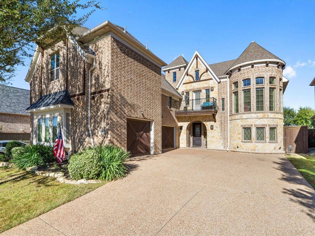 1506 Hennessey Drive, Allen, TX 75013 This stunning French country-inspired facade boasts a charming balcony, warm brick siding, and an expansive three-car garage, complete with a beautiful, lengthy driveway perfect for accommodating additional guest parking.