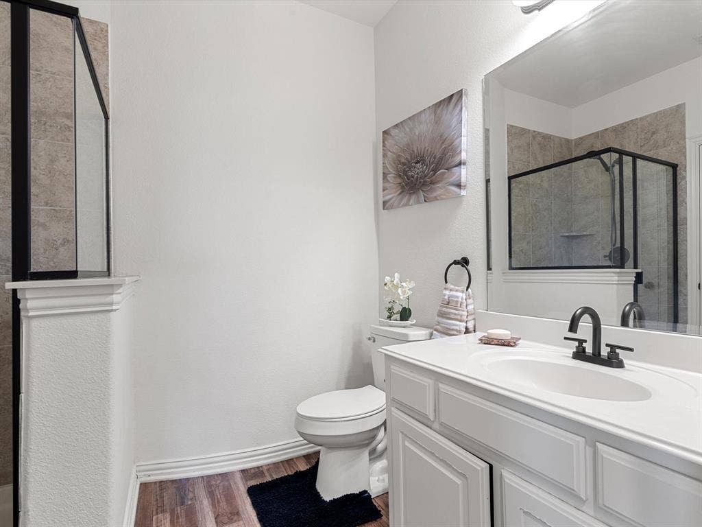 1506 Hennessey Drive, Allen, TX 75013 Bathroom with dark wood finished floors, a shower stall, vanity, and a textured wall