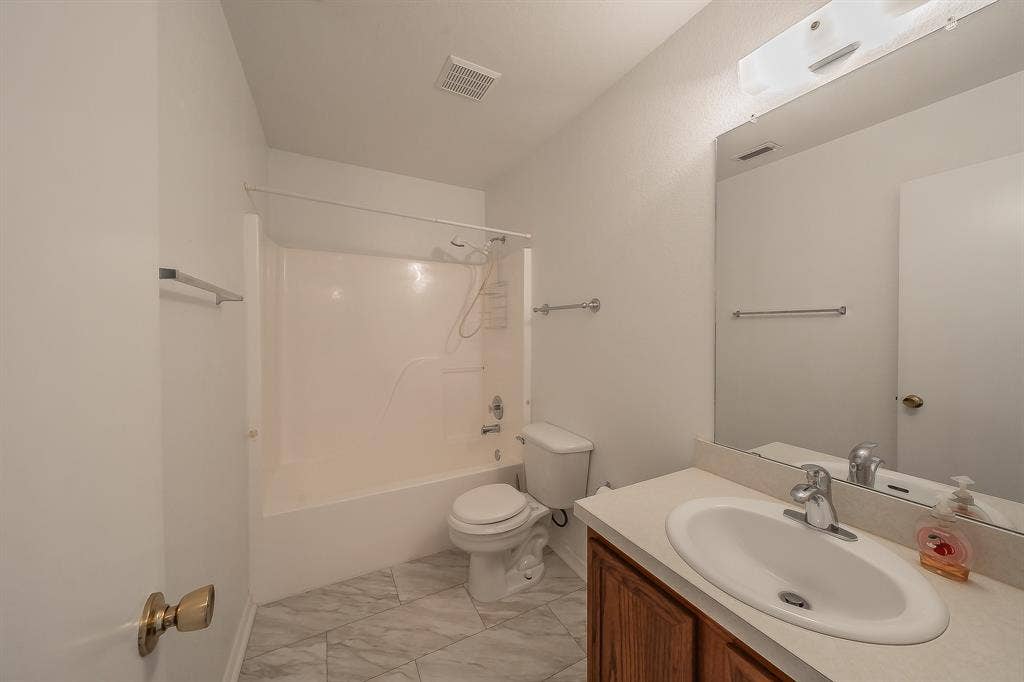 6833 Bluff View Drive, Watauga, TX 76137 Bathroom featuring a vanity with an integrated basin, wood-finish cabinetry, a large wall-mounted mirror, and tile flooring arranged in a diagonal pattern