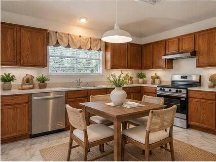 6833 Bluff View Drive, Watauga, TX 76137 Kitchen featuring wood cabinetry, stainless steel appliances, white solid-surface countertops, pendant lighting, and tile flooring