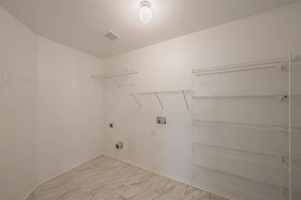 6833 Bluff View Drive, Watauga, TX 76137 Utility area featuring stone-patterned tile flooring, multi-tier wire shelving, and dedicated utility hookups