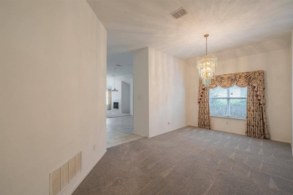 6833 Bluff View Drive, Watauga, TX 76137 Formal room featuring neutral carpeting, a tiered crystal chandelier, and a large window