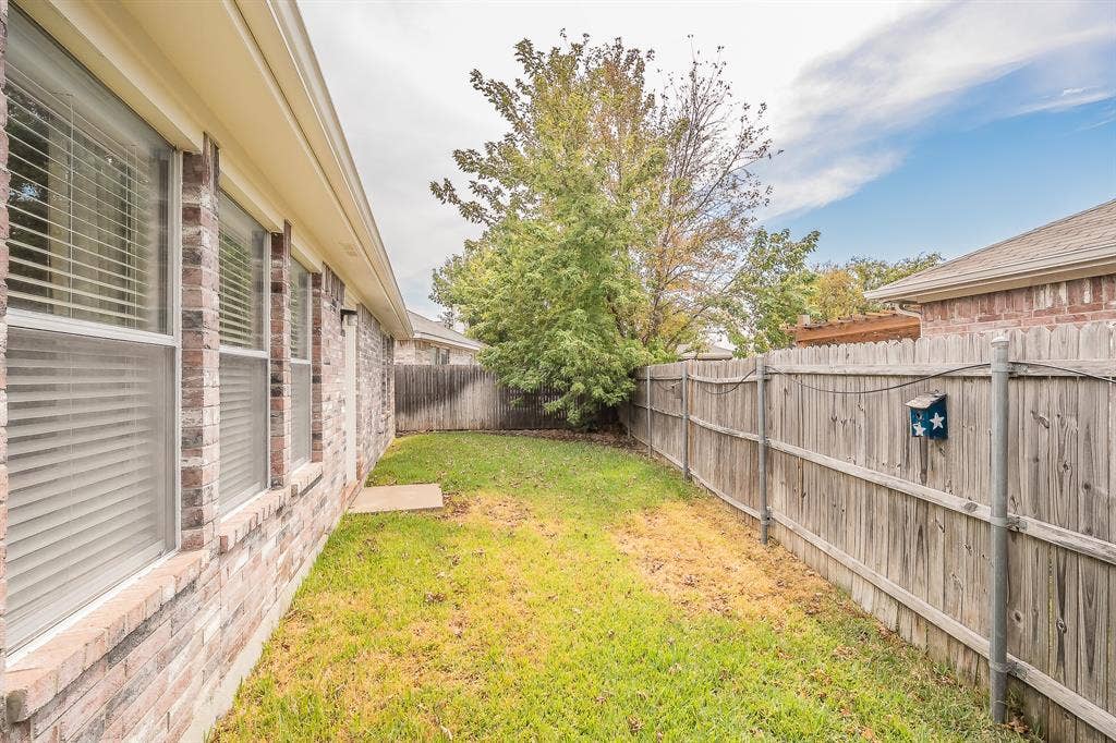 6833 Bluff View Drive, Watauga, TX 76137 Exterior side yard featuring brick masonry, horizontal wood fencing, and mature trees