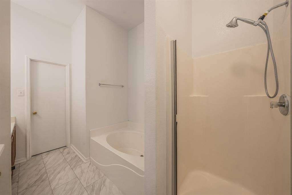 6833 Bluff View Drive, Watauga, TX 76137 Bathroom featuring a separate soaking tub, walk-in shower with a handheld fixture, tile flooring, and a wall-mounted towel bar