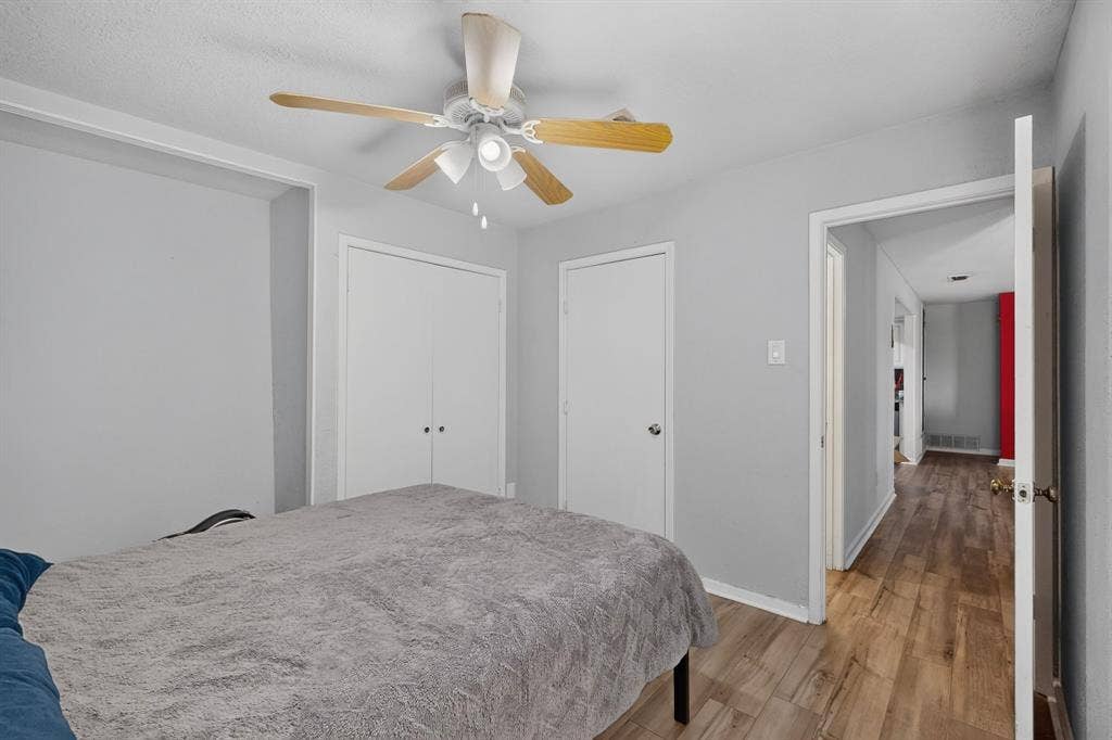 2228 Bunker Hill Drive, Carrollton, TX 75006 Interior room featuring wood-finish flooring, a ceiling fan with integrated lighting, and dual closet storage