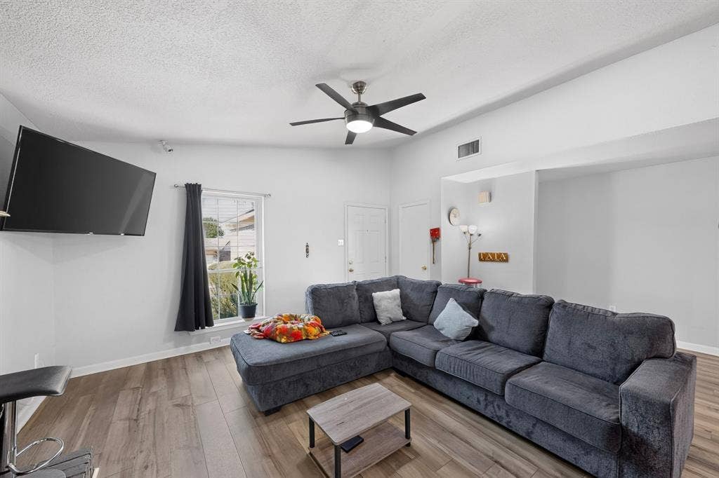 2228 Bunker Hill Drive, Carrollton, TX 75006 Living area featuring wood-finish flooring, vaulted ceilings, and a ceiling fan with integrated lighting