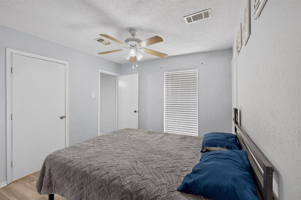 2228 Bunker Hill Drive, Carrollton, TX 75006 Neutral-toned walls paired with wood-finish flooring, featuring a ceiling fan with integrated lighting and horizontal window blinds