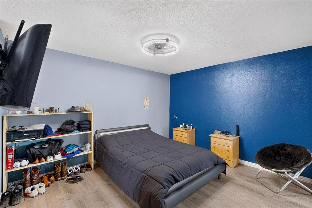 2228 Bunker Hill Drive, Carrollton, TX 75006 Room featuring wood-finish flooring, a deep blue accent wall, and a low-profile circular flush-mount ceiling fixture with an integrated fan