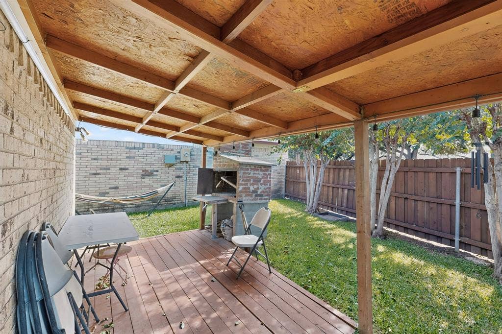 2228 Bunker Hill Drive, Carrollton, TX 75006 Covered outdoor deck with wood-finish flooring, exposed timber ceiling beams, and a built-in masonry grill