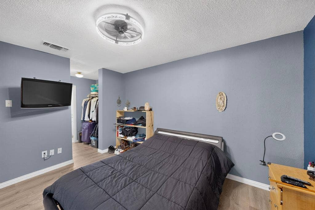 2228 Bunker Hill Drive, Carrollton, TX 75006 Neutral-toned interior featuring wood-finish flooring, textured walls, and a contemporary ceiling fan with an integrated light fixture