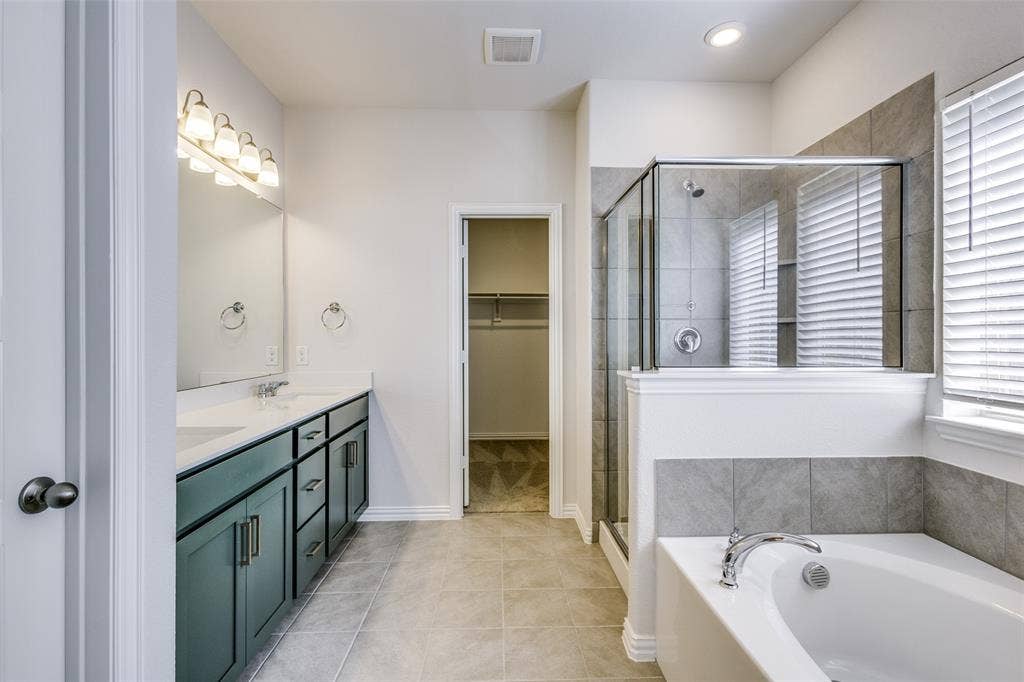 3325 Cross Shore Drive, Anna, TX 75409 Bathroom featuring tile patterned floors, a spacious closet, a shower stall, double vanity, and a garden tub
