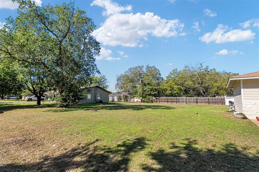 519 MAE Drive, Mabank, TX 75147 Expansive backyard featuring a large grass lawn, mature trees, and wooden perimeter fencing