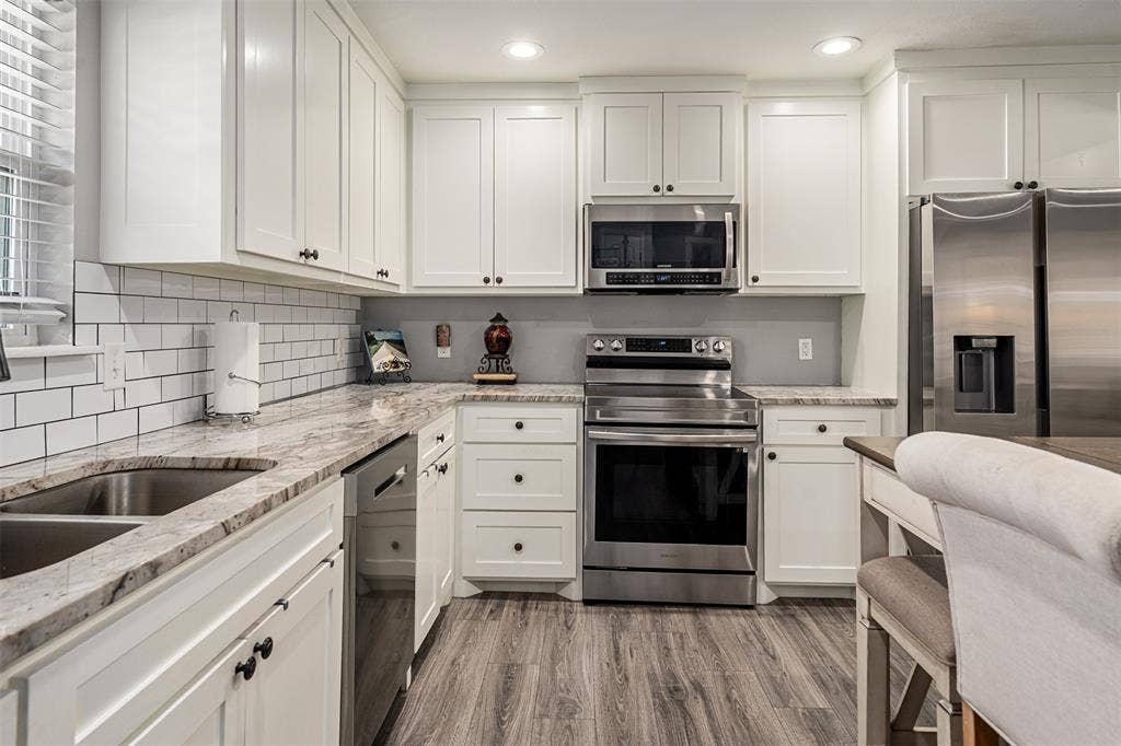 519 MAE Drive, Mabank, TX 75147 Kitchen featuring white shaker cabinetry, stone-surface countertops, subway tile backsplash, stainless steel appliances, and wood-finish flooring