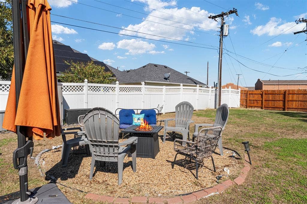 519 MAE Drive, Mabank, TX 75147 Backyard featuring a circular gravel patio area with a brick-paver border and a white vinyl perimeter fence