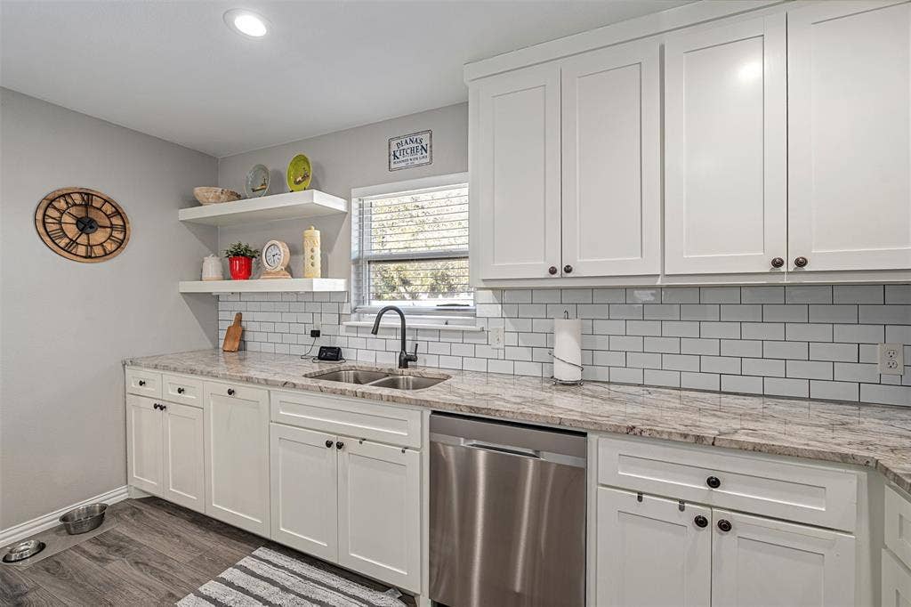519 MAE Drive, Mabank, TX 75147 Kitchen featuring white shaker-style cabinetry, stone-patterned countertops, subway tile backsplash, floating shelving, and stainless steel dishwasher