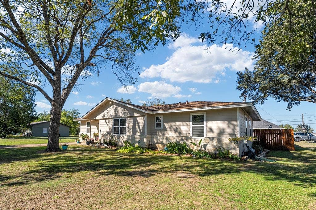 519 MAE Drive, Mabank, TX 75147 Single-story exterior featuring light-toned horizontal siding, stone veneer lower accents, a composition shingle roof, and mature trees on the surrounding lot