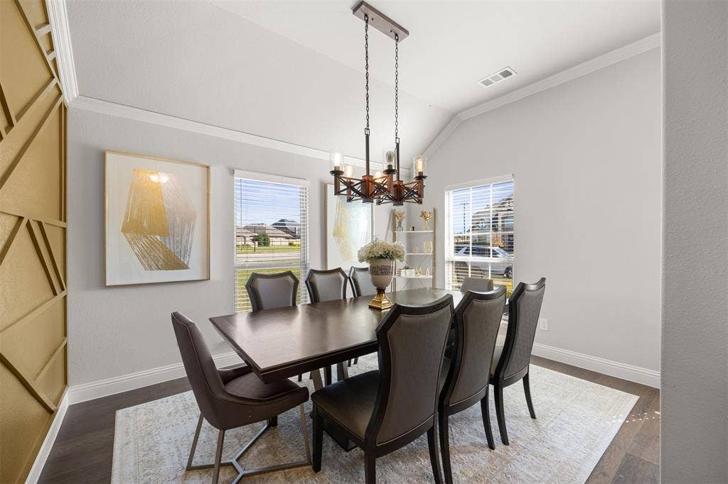 Vaulted ceiling, decorative geometric wall paneling, multi-light chandelier, and wood-finish flooring