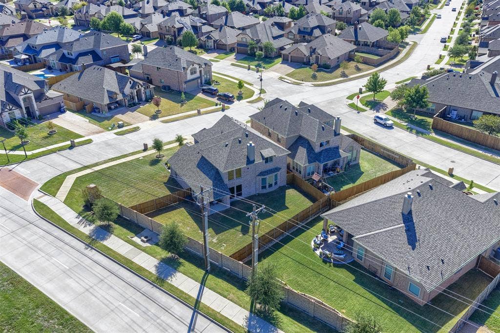 Corner lot residence featuring a masonry exterior, multi-pitched shingle roof, expansive fenced-in backyard, and concrete sidewalk access