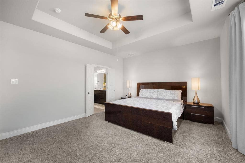 Tray ceiling featuring a central multi-blade ceiling fan with integrated lighting and neutral carpeting