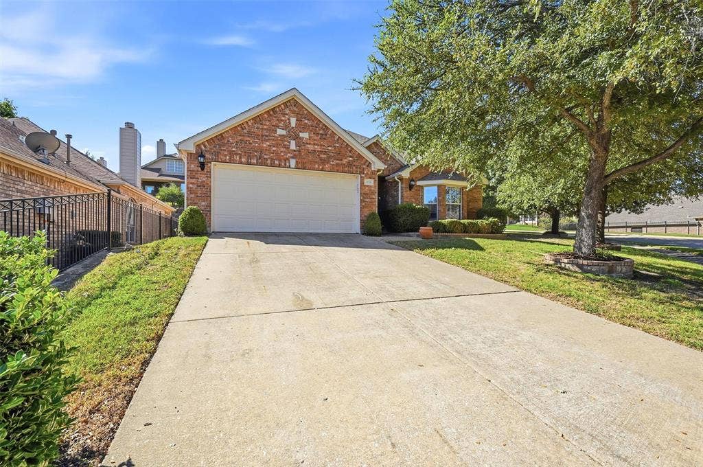 819 Mustang Drive, Fairview, TX 75069 Brick exterior with gable roofline, two-car garage, concrete driveway, and mature landscaping