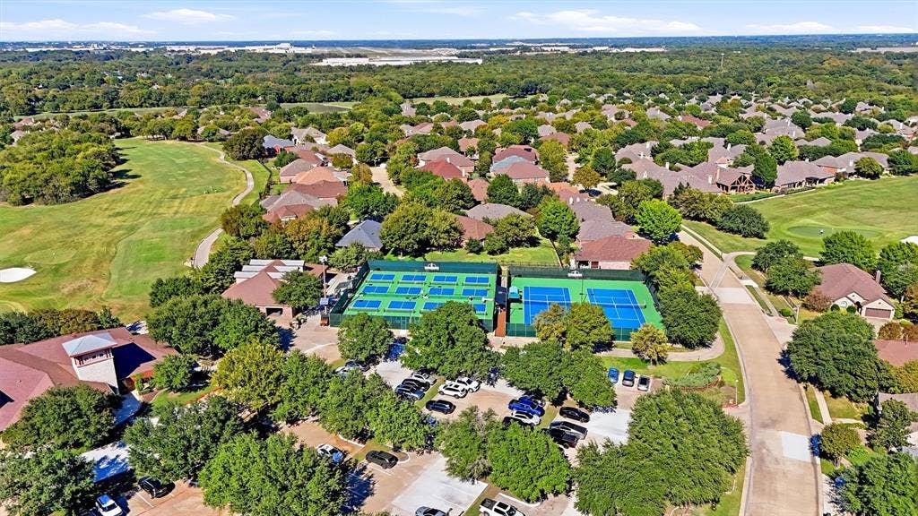 819 Mustang Drive, Fairview, TX 75069 Aerial perspective of tennis courts, paved parking area, and surrounding green space with mature trees