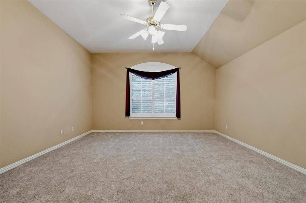 819 Mustang Drive, Fairview, TX 75069 Owner's suite, featuring vaulted ceiling, carpeting, ceiling fan with integrated lighting, and an arched window