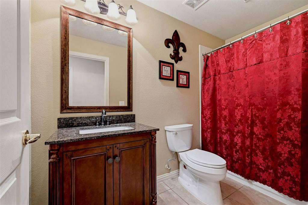 819 Mustang Drive, Fairview, TX 75069 Bathroom featuring a wooden vanity, stone countertop, undermount sink, matching framed mirror, and tiled flooring