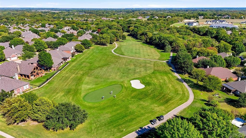 819 Mustang Drive, Fairview, TX 75069 Aerial perspective of a golf course featuring manicured putting greens, sand bunkers, paved cart paths, and established tree canopy