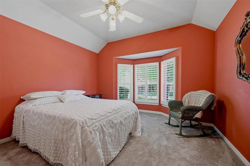 819 Mustang Drive, Fairview, TX 75069 Vaulted ceiling featuring a central lighted ceiling fan, bay window with plantation shutters, and neutral carpeting