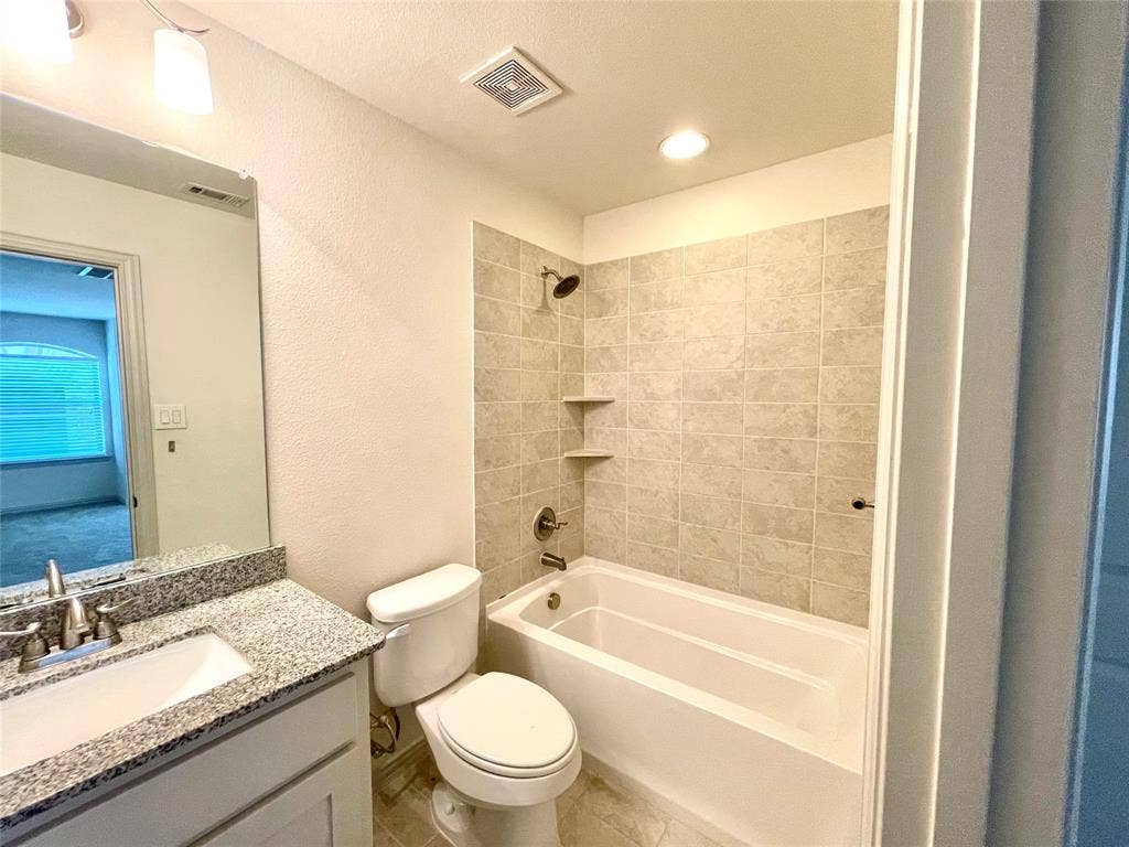 4213 Arbrook Way, Plano, TX 75074 Full bathroom featuring a stone-composite countertop with an integrated sink, large wall-mounted mirror, white cabinetry, and a shower-tub combination with tiled surround walls and built-in shelving