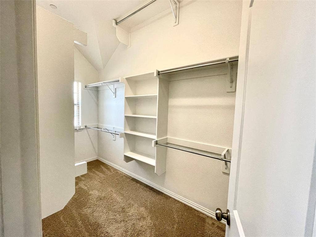 4213 Arbrook Way, Plano, TX 75074 Walk-in closet featuring vaulted ceilings, built-in shelving, multiple hanging rods, and carpeting