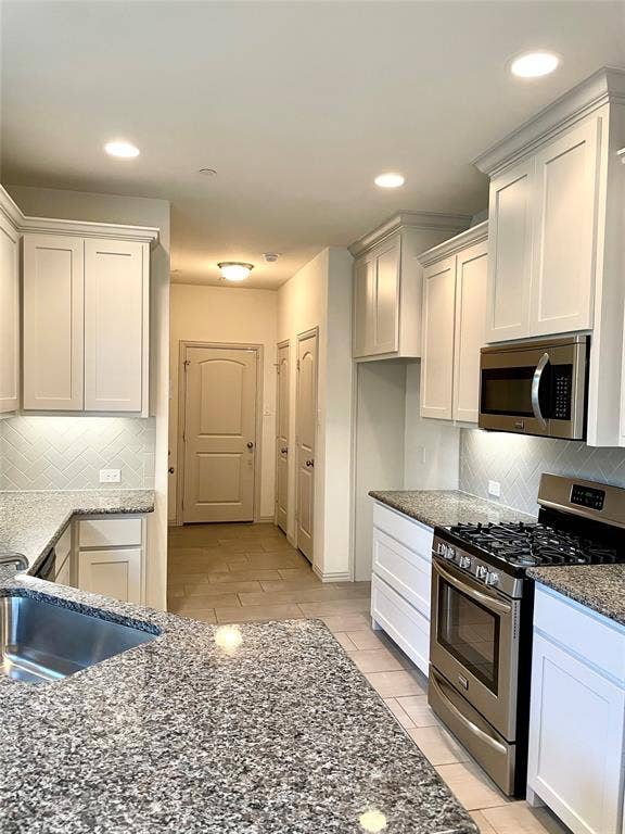 4213 Arbrook Way, Plano, TX 75074 Kitchen featuring white shaker-style cabinetry, stone countertops, stainless steel appliances, a herringbone-patterned tile backsplash, and recessed lighting
