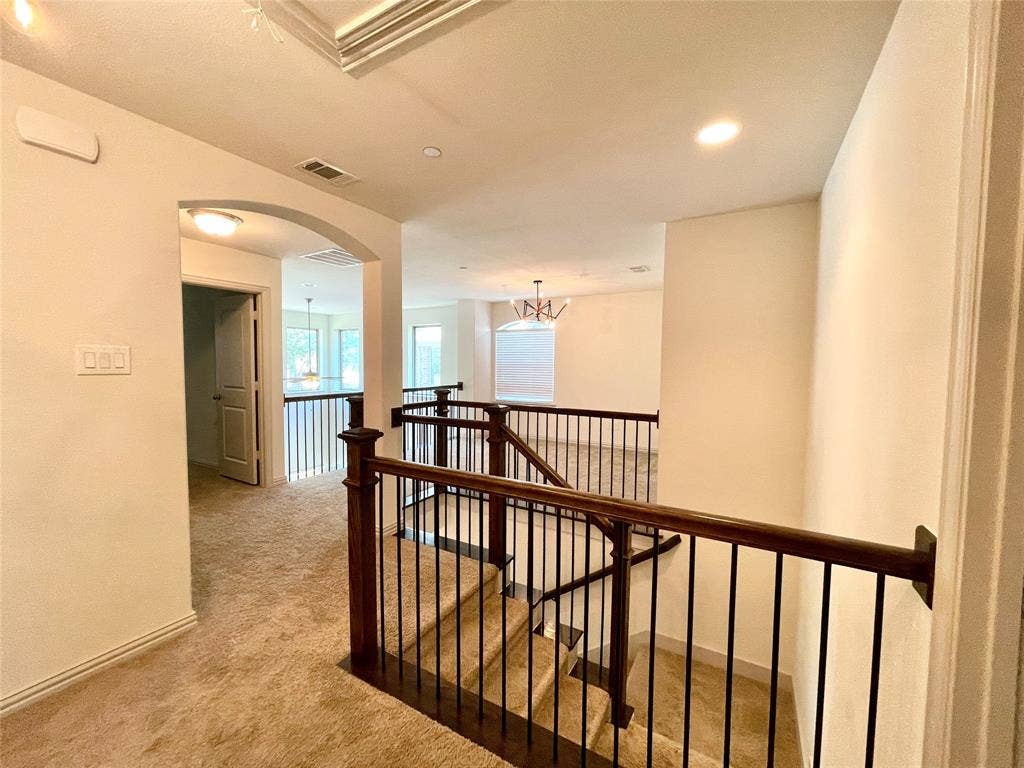 4213 Arbrook Way, Plano, TX 75074 Staircase featuring dark wood handrails with metal balusters, arched architectural detail, recessed lighting, and wall-to-wall carpeting