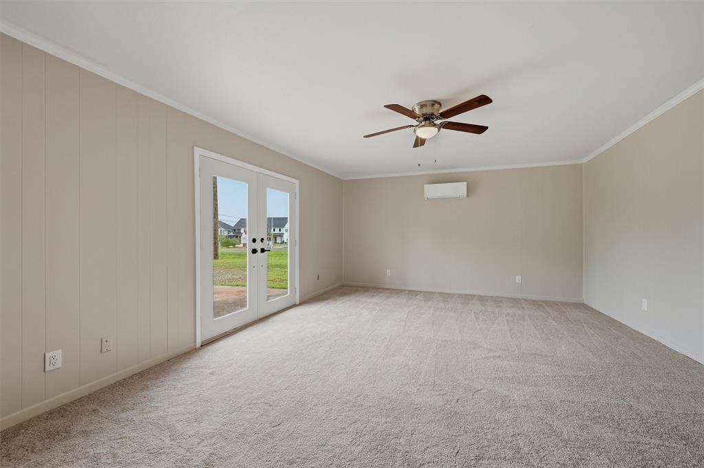 607 N Louisiana Drive, Celina, TX 75009 Neutral-toned interior featuring wall-to-wall carpeting, vertical paneling, a multi-speed ceiling fan with integrated lighting, and a wall-mounted ductless heating and cooling unit, complete with a glass-paneled exterior door