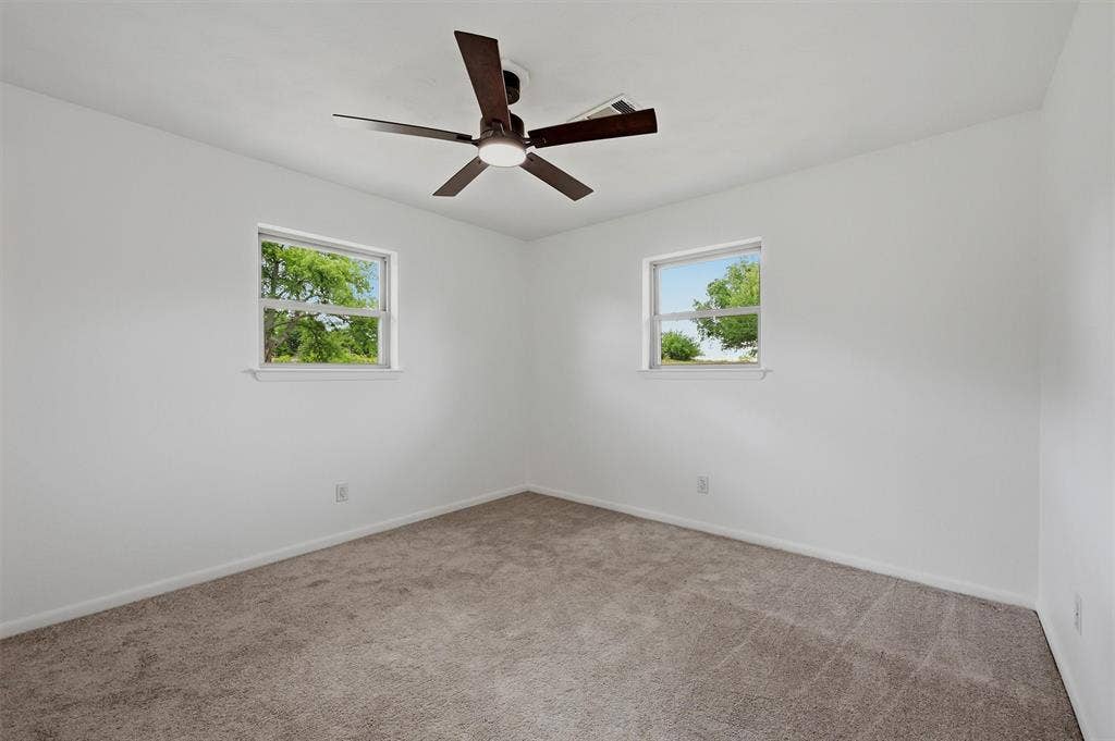 607 N Louisiana Drive, Celina, TX 75009 Neutral interior featuring plush wall-to-wall carpeting, two dual-pane windows, and a central ceiling fan with integrated light fixture