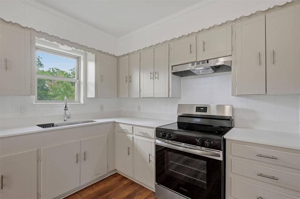 607 N Louisiana Drive, Celina, TX 75009 Kitchen featuring solid-surface countertops, wood-finish flooring, shaker-style cabinetry with satin nickel pulls, a stainless steel range, and a drop-in sink with a high-arc faucet