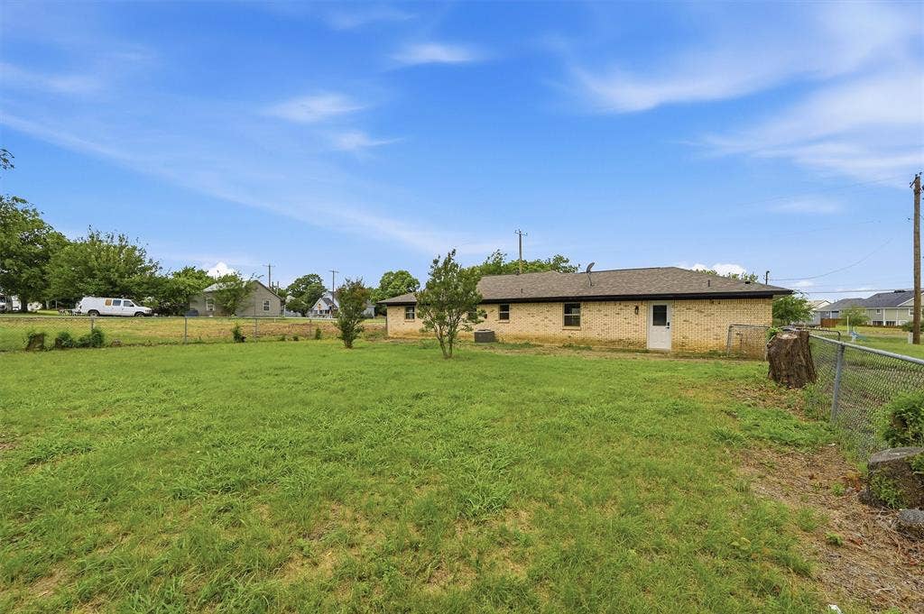 607 N Louisiana Drive, Celina, TX 75009 Expansive backyard featuring a grass lawn, chain-link fencing, masonry exterior walls, and a shingle roof